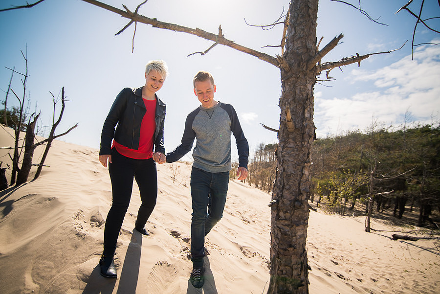 Photograph of Liz & Jason walking hand in hand on the sand for their pre wedding shoot. Photographed by Celynnen Photography.