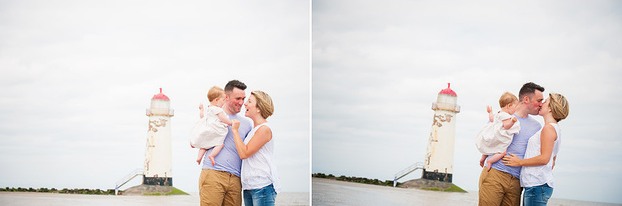 Couple laughing and kissing on the beach with the lighthouse in the back. Portrait photography session in Mold, North Wales