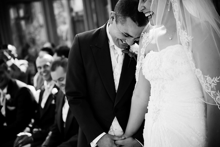 the bride and groom laughing and holding hands during ceremony in the conservatory at Seiont Manor in Caernarfon (Ioan Said / Celynnen Photography)