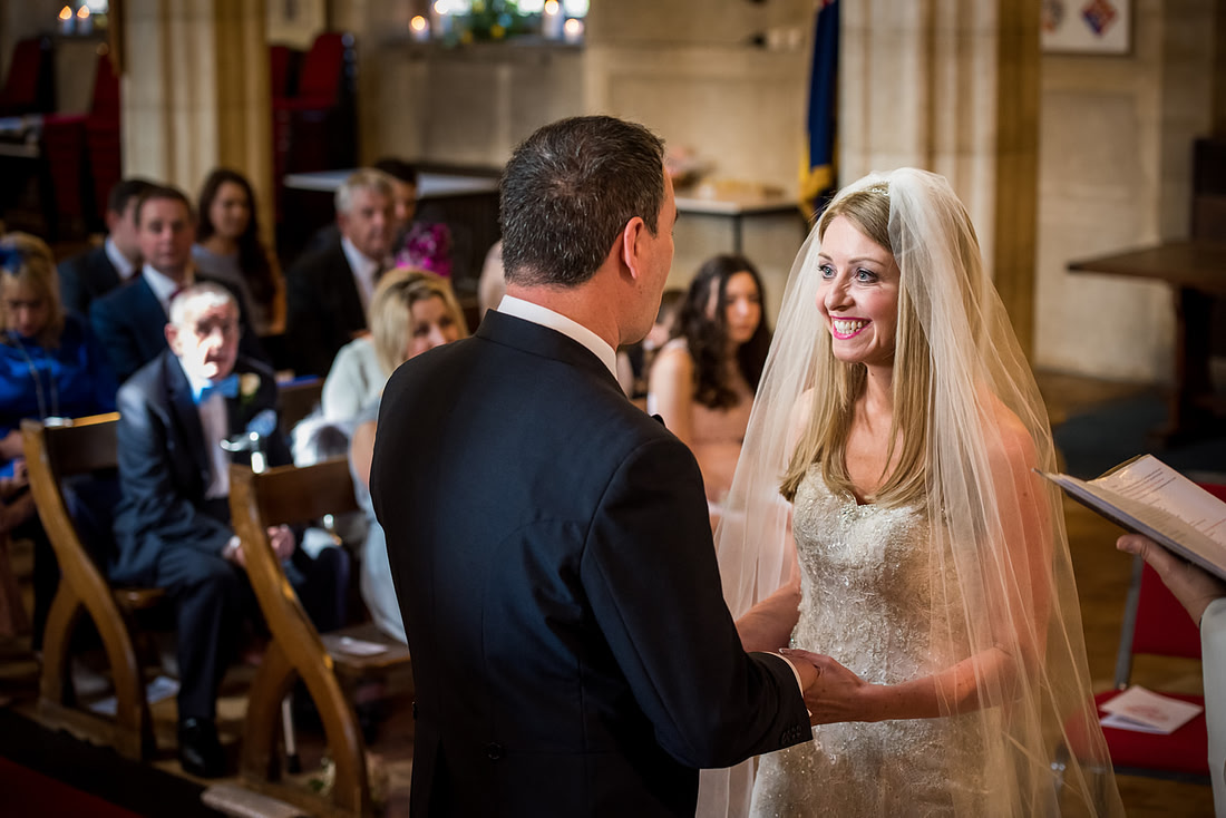 Image of the bride smiling at the groom during their wedding ceremony in a church in Buckinghamshire.