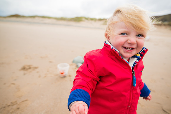 A little boy having fun on a day out to Deganwy beach with Celynnen Photography