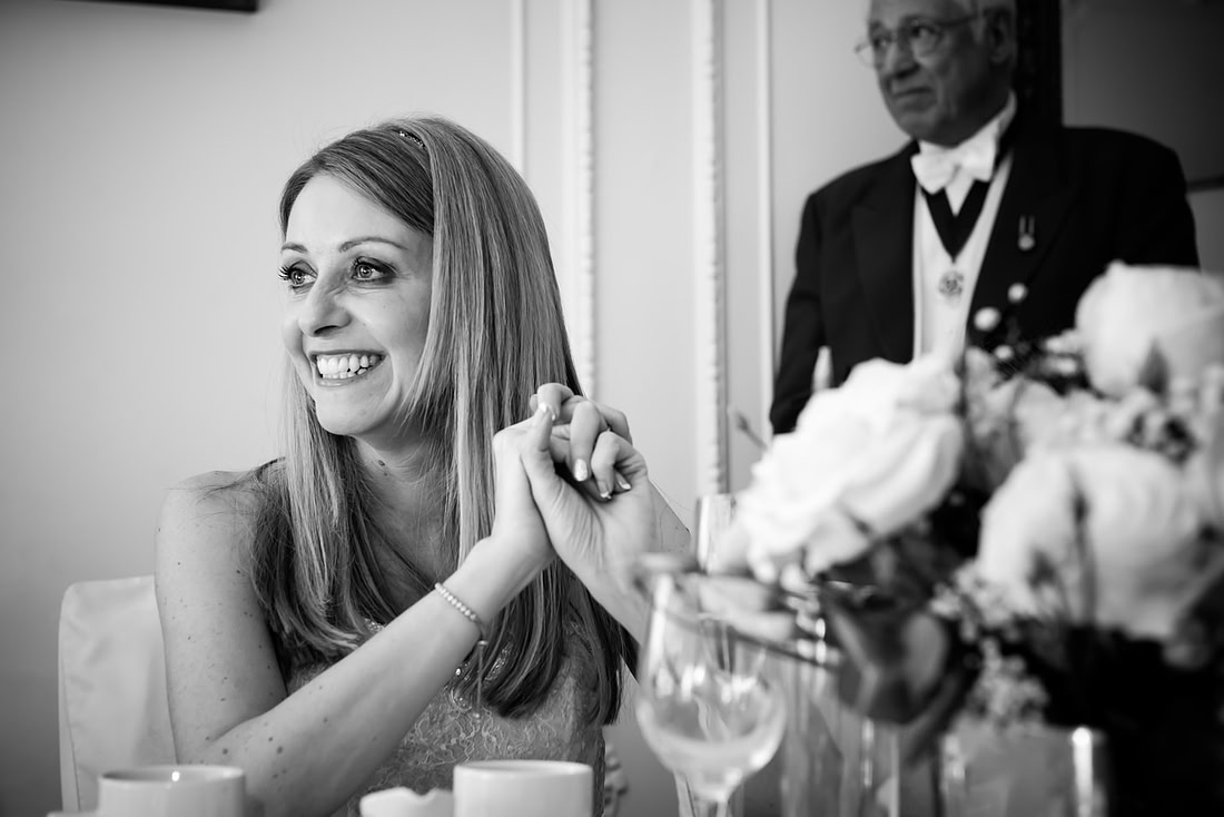 Black and white image of the bride smiling during the speeches at a wedding at Taplow House, Buckinghamshire.