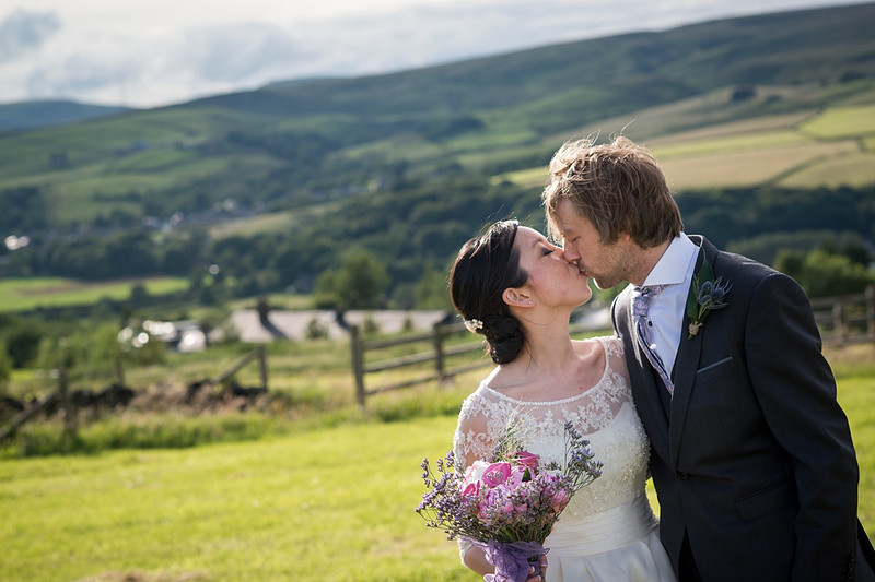 Bride and groom kissing with North Wales scenery in the background.
