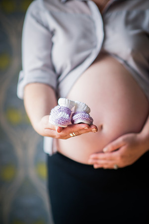 Woman holding tiny shoes for her future baby during her bump to baby photoshoot