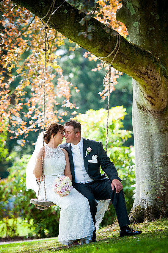 Bride and groom sitting on a swing on their wedding day in Chateaux Rhianfa, Anglesey. Wedding Photographer, Celynnen Photography