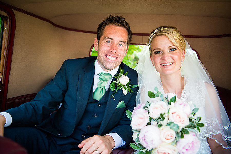 Bride and groom in their wedding car about to go to their wedding reception at Llyndir Hall, Chester.