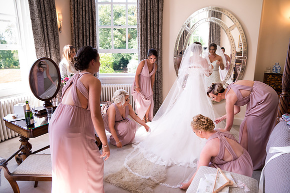 Friends of the Bride are Holding Her Dress Before the Main Event.