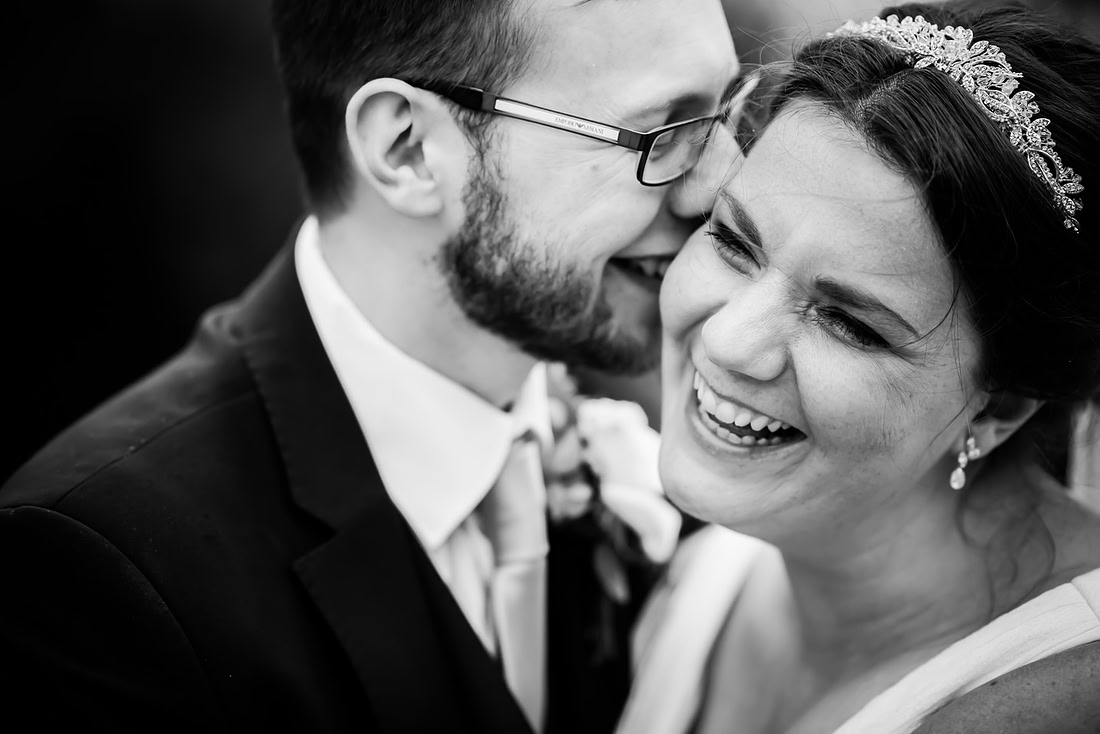Black and white image of the groom whispering something in the bride's ear at a wedding at Mere Brook House.