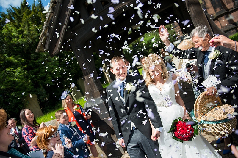 Image of the bride and groom getting showered with confetti after their wedding ceremony in Davenham.