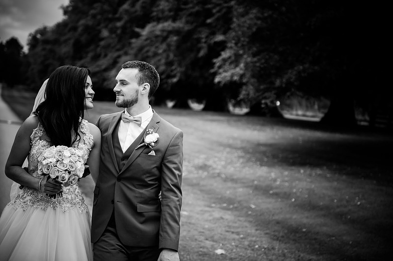 Black and white image of the bride and groom walking around the grounds of Soughton Hall.