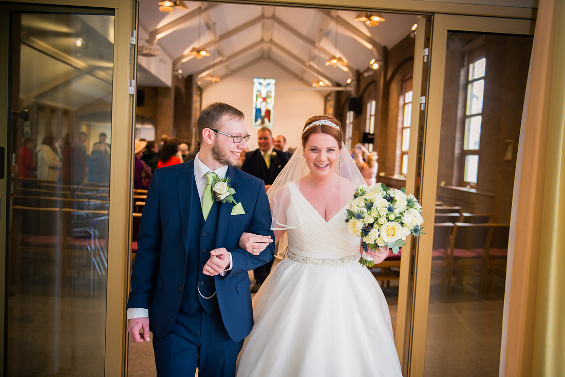 Image of the groom glancing at his new wife as they leave the wedding ceremony.