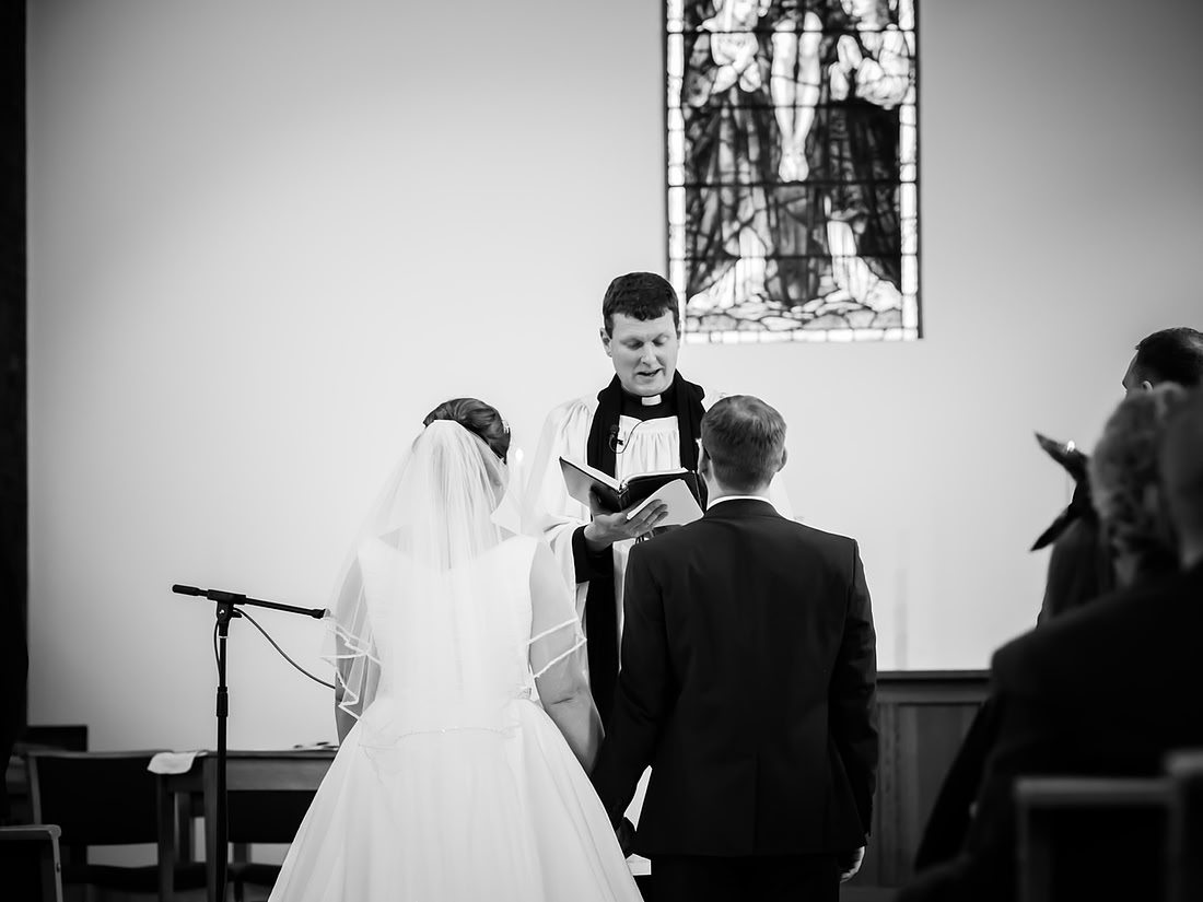 Black and white image of the back of the bride and groom during the wedding ceremony.