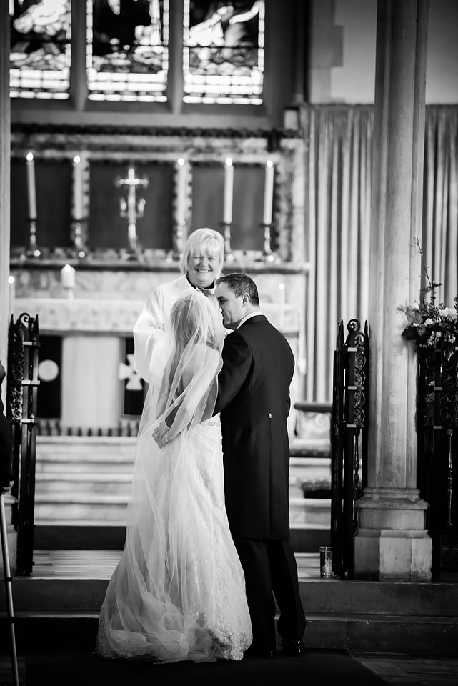 Black and white image of the bride and groom sharing a kiss in a church in Buckinghamshire