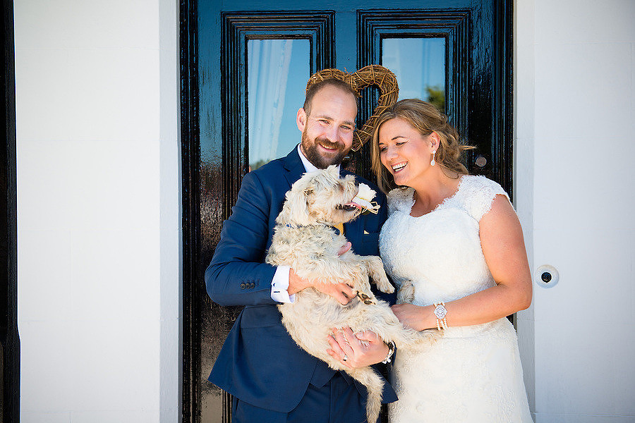 Bride and groom having a photo with their dog on their wedding day in Anglesey.