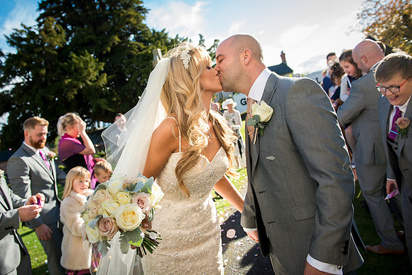 A couple sharing a kiss surrounded by friends and family in sunny North Wales at the White House in Rhuallt