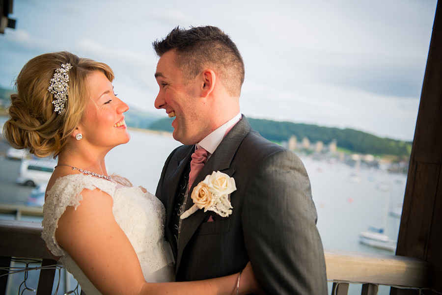 bride and groom laughing on the balcony at the Deganwy Quay. Wedding Photographer: Celynnen Photography