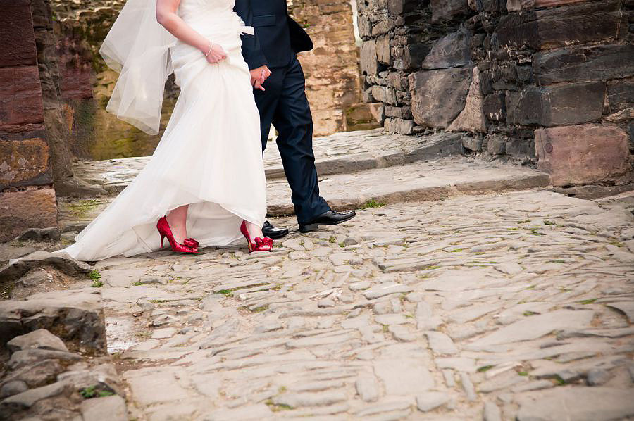 Red Shoes. Bride and groom walking after wedding at conwy castle