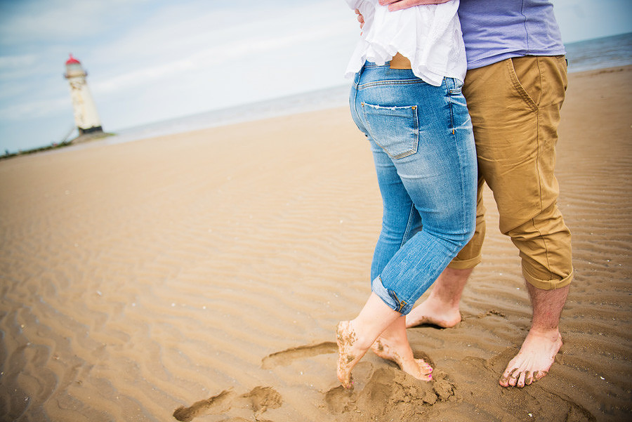 couple kissing on the sandy beach of talacre near mold, with the lighthouse in the background