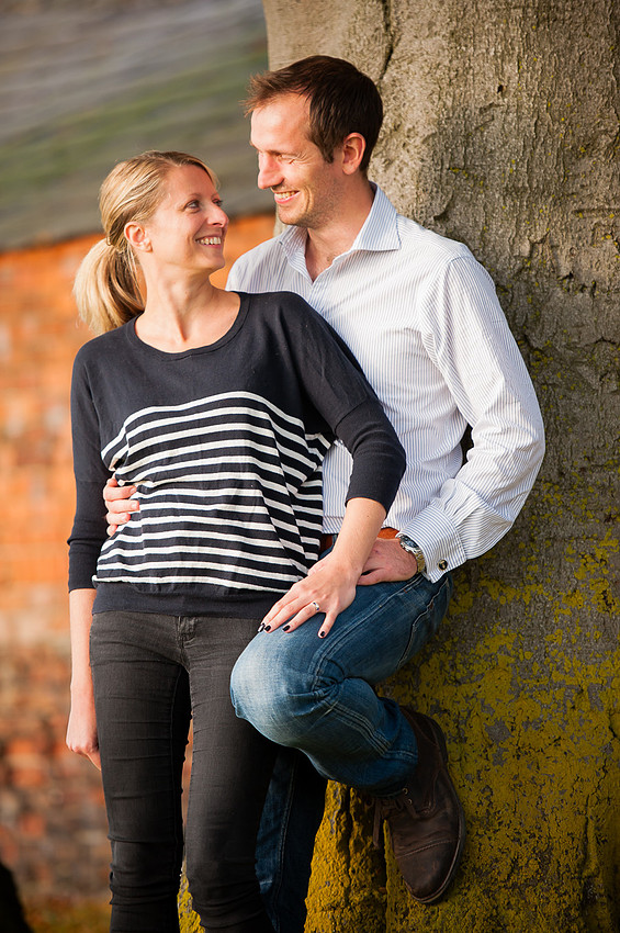 Portrait of a couple leaning against a tree while smiling at each other in Chester.