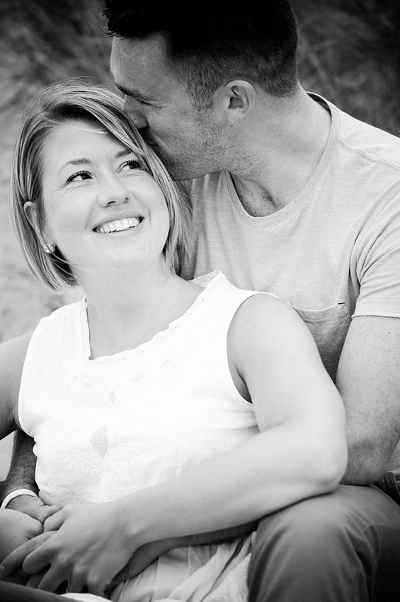 Lee kissing Lowri on the head during a break in their portrait session at talacre beach by Mold, North Wales