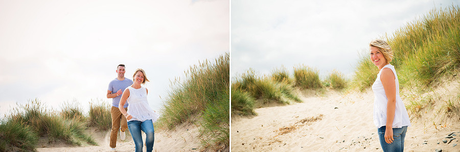 Couple chasing each other on the sand dunes of talacre beach in North Wales during their portrait session near mold