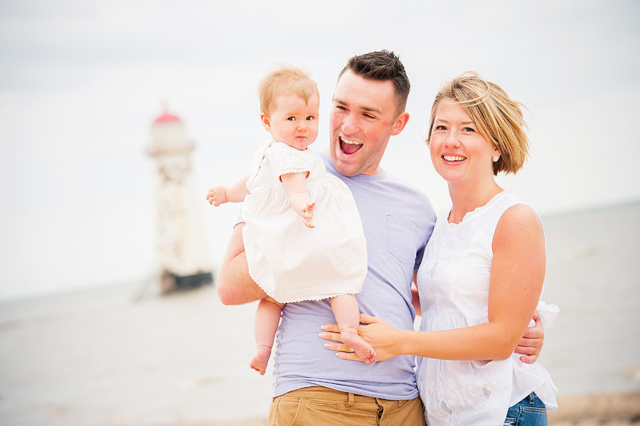 young family posing and smiling for the camera during their pre-wedding portrait session at Talacre Beach near Mold, North Wales