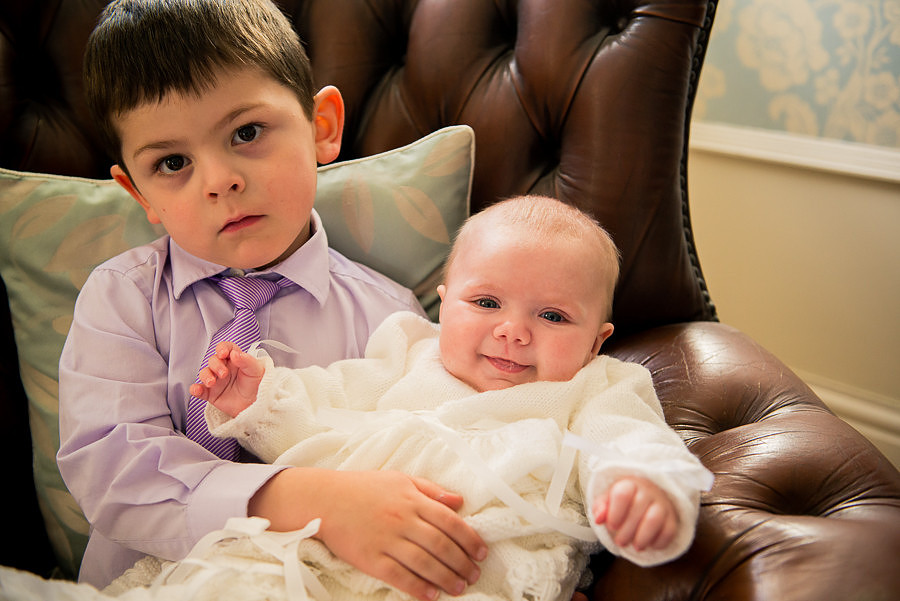 Amelia being held by a friend while sitting on a leather chair, taken at Trearddur Bay Hotel by Celynnen Photography.
