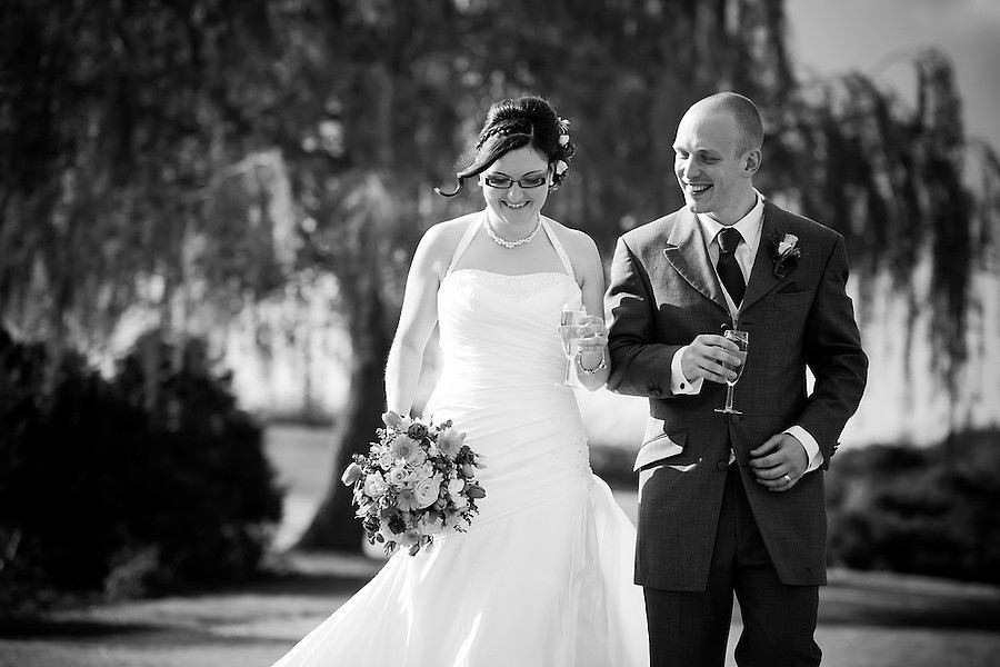 Black and white image of the bride and groom walking around the grounds of Holt Lodge.
