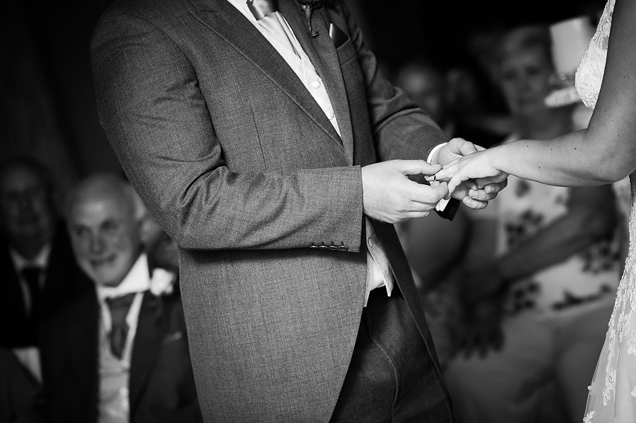 Black and white image of the exchanging of the wedding rings at a wedding at Grosvenor Pulford